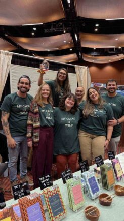 Luisa Abram and her family smiling at their Northwest Chocolate Festival booth with award-winning white chocolate bar.